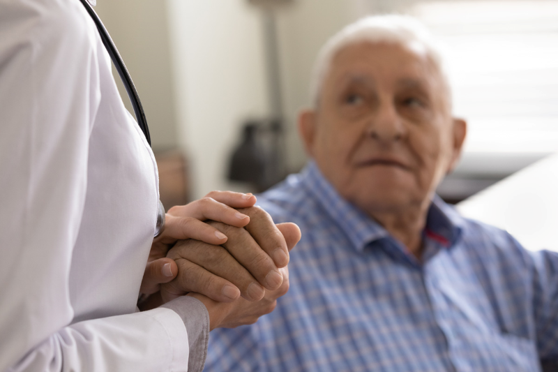 elderly man holding doctor's hand