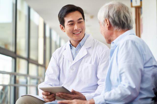Asian physician conversing with elderly man