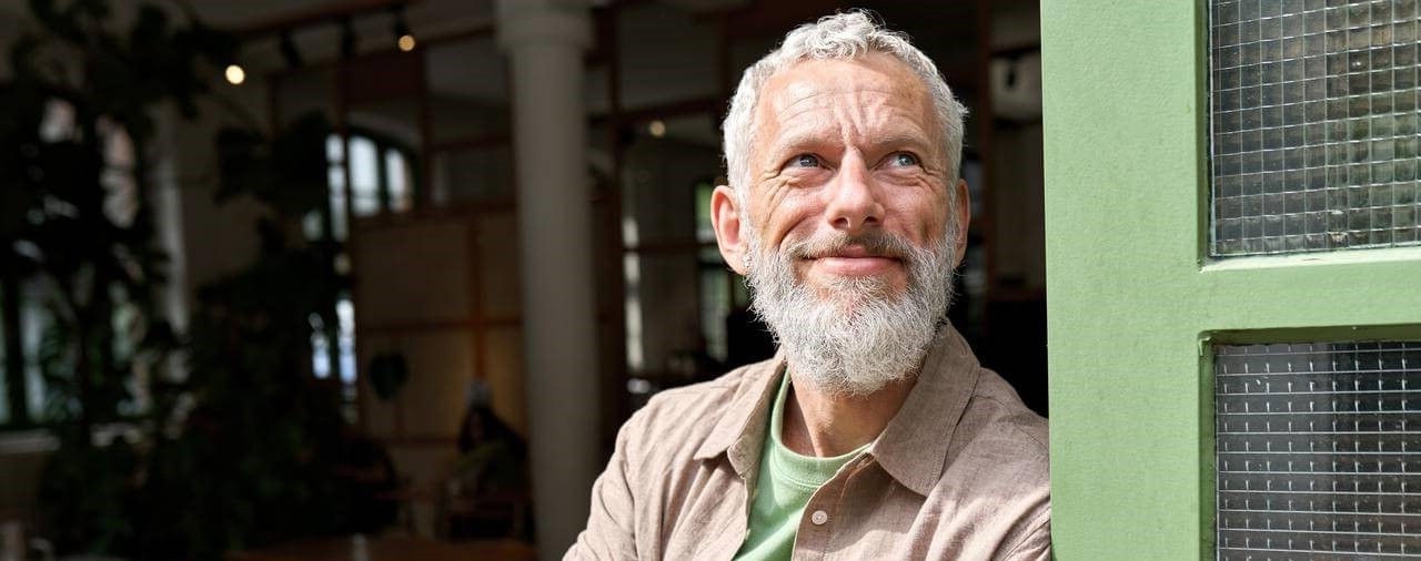 Senior entreprenuer smiling leaning against opening of business