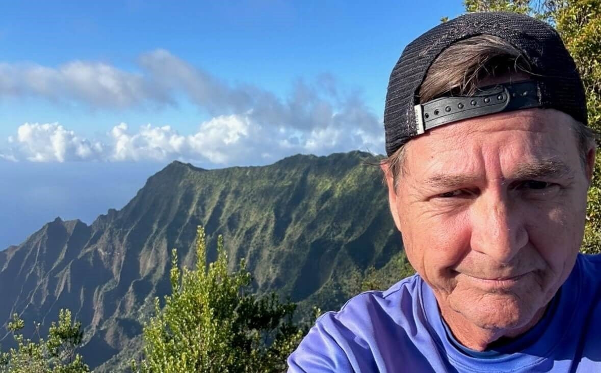 Scott taking a selfie with mountain scenery in view after a long bike ride