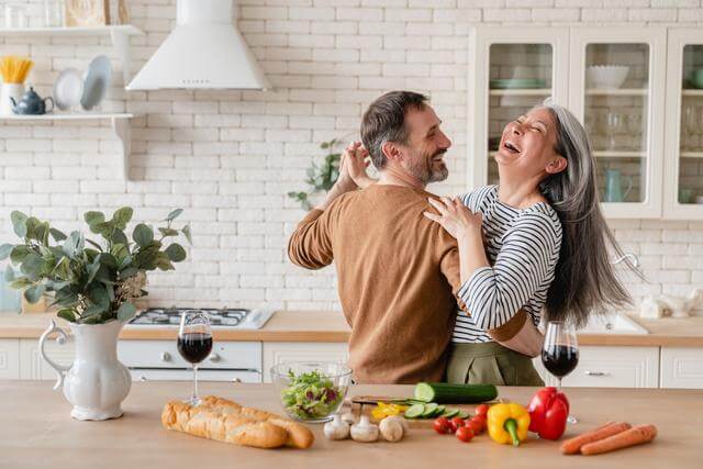 caucasian couple dances in the kitchen while making a fresh meal